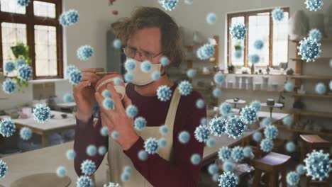 animación de las células de covid-19 sobre el hombre que trabaja en el estudio de cerámica con máscara facial