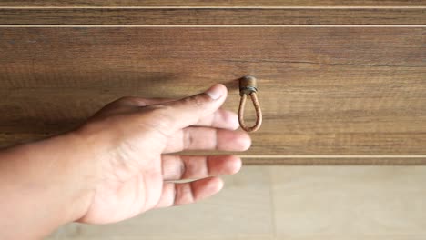 hand opening a wooden drawer