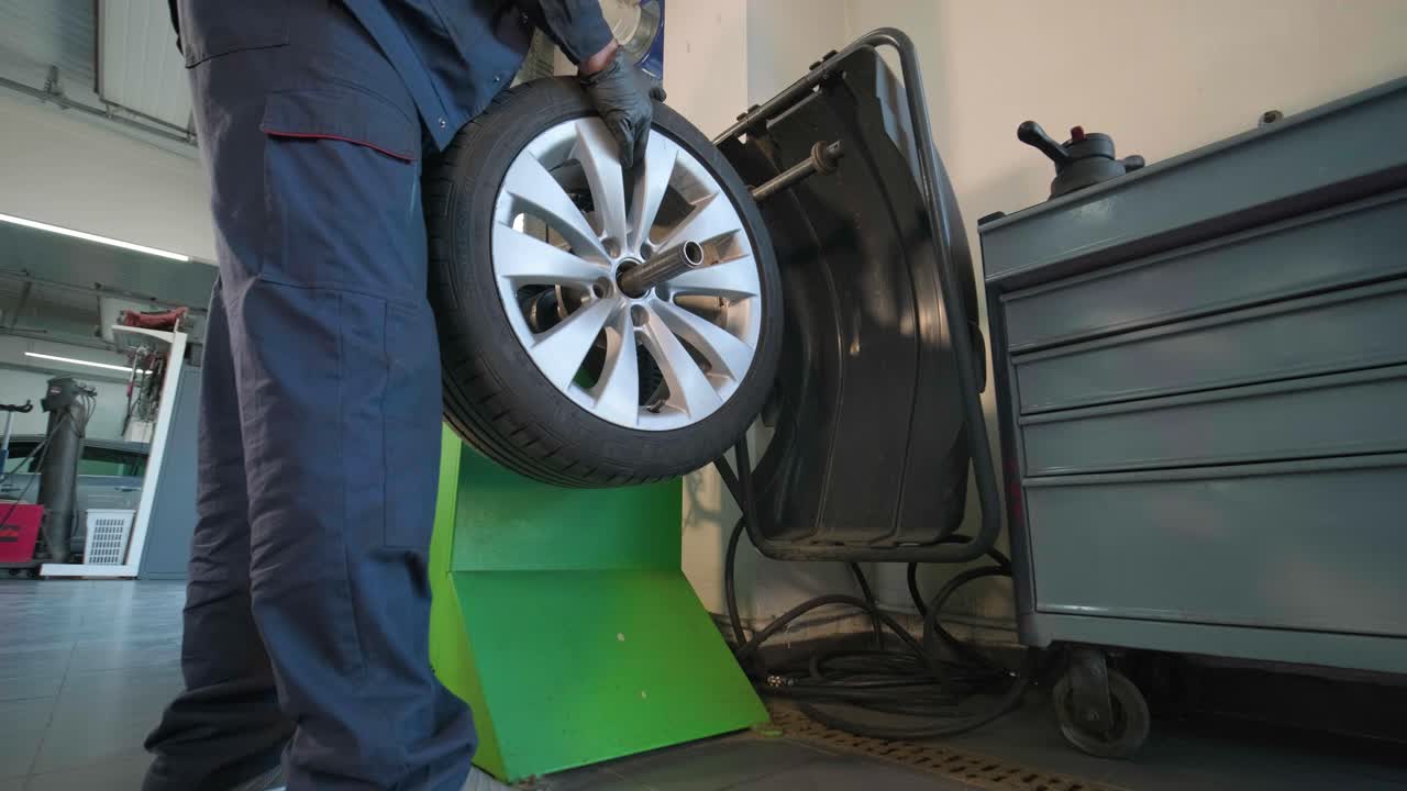 manos del mecánico con la herramienta, cambiando el neumático del coche en el servicio de automóviles