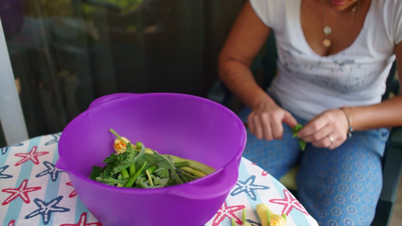 야외에서 주키니 꽃을 준비하고 청소하는 백인 여성의 영상