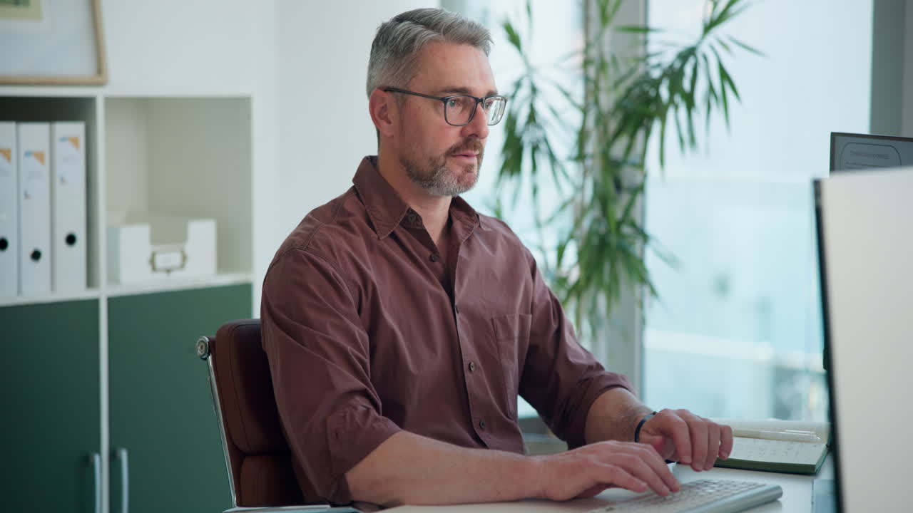 Fokuseret mand arbejder på computer ved skrivebord på moderne kontor