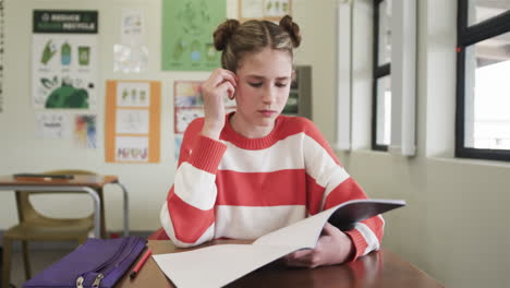 young girl in classroom covering face with hands, feeling stressed during study, at school