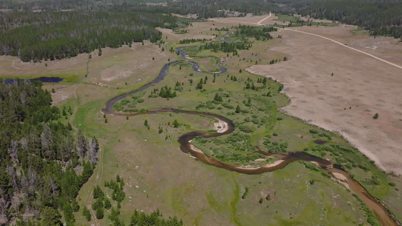 Aerial view of meandering river of Big Sandy Trailhead in the Wind River Wilderness, Wyoming, showcasing vast green plains and mountainous terrain