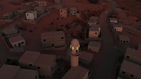 aerial view at morning of an empty arabic city near gaza in palestine with mosque with green shining lights revealing rest of the city.