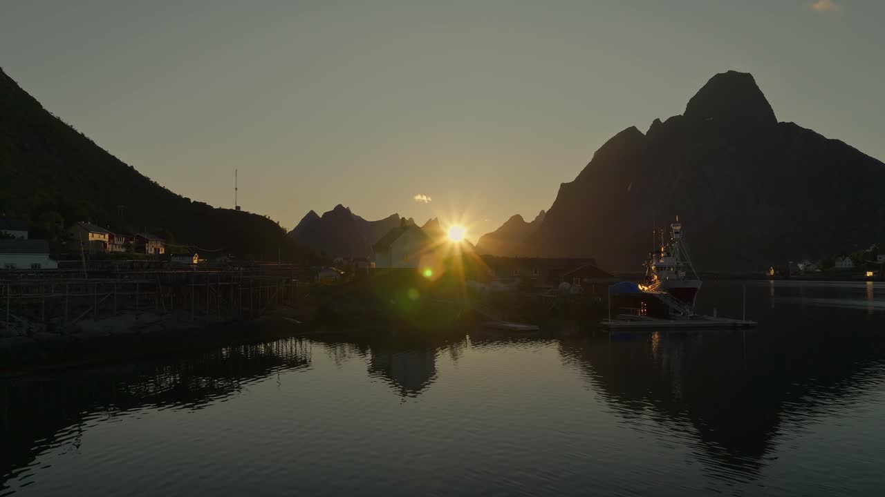 로포텐의 마을과 산 뒤에 해가 지는 모습, 공중에서 낮은 각도에서 볼 수 있습니다.