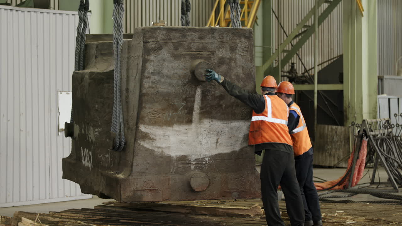 Workers lifting a heavy metal object using a crane
