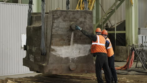 workers lifting a heavy metal object using a crane