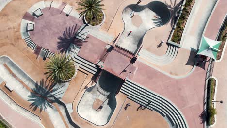 warm sunlit public skate park with palm trees aerial descending birdseye view