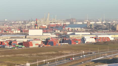 vista aérea ampliada de camiones que conducen por la autopista con el puerto de rotterdam en el fondo
