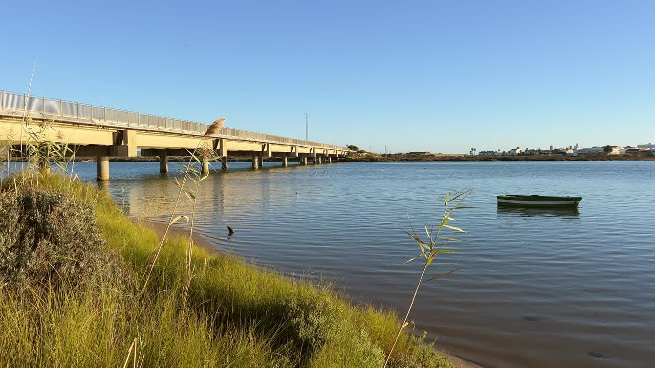 Wide shot of a bridge spanning calm ocean waters with a single boat anchored at the center