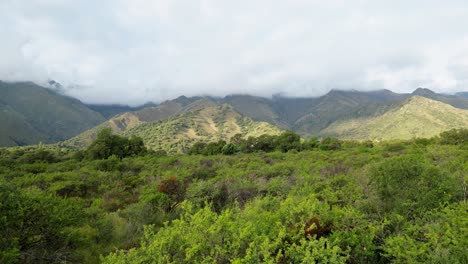 Stunning-drone-footage-soaring-over-mountainous-terrain,-showcasing-lush-vegetation-and-majestic-mountain-ranges