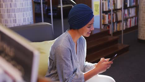 Asian-female-student-wearing-a-blue-hijab-sitting-and-using-a-smartphone