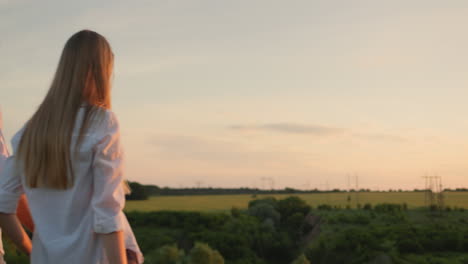 friends meet the sunset in a picturesque place, hold hands and raise them up