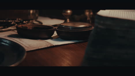 an old compass on the table filled with documents and maps inside the sailing ship cabin