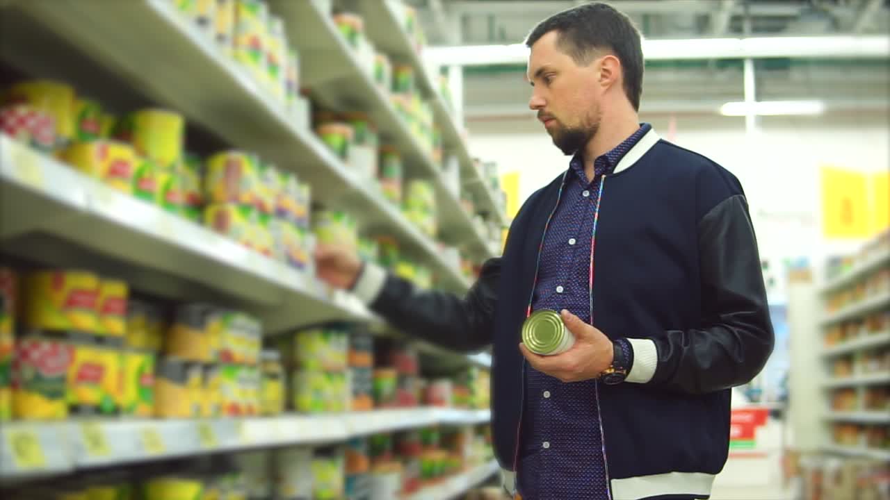 hombre comprando productos enlatados en una tienda de comestibles