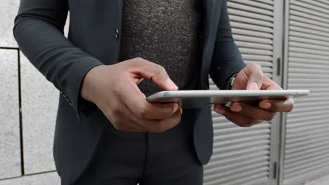 businessman typing on tablet on city street. executive using tablet on street