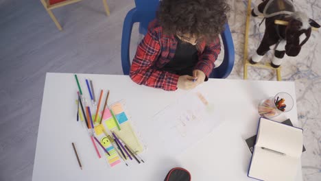 el niño dibuja un cuadro de su familia en papel.