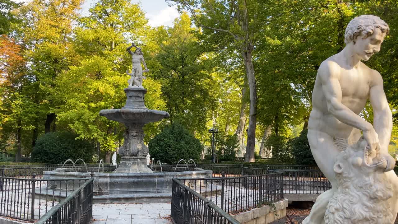 filming of the fountain of Hercules and the Hydra in the palace gardens, 2 sculptures at the entrance to the fountain appear in the foreground, closed with a fence and high up, Hercules fighting