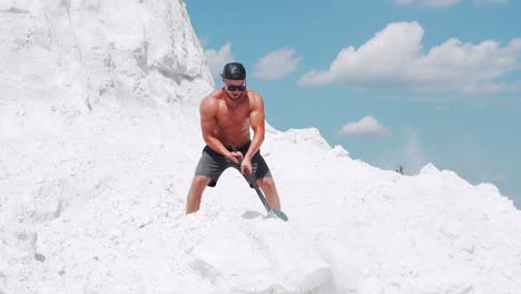 athlete man in shorts doing exercises with a sledgehammer breaks stones. outdoor activities. slow motion
