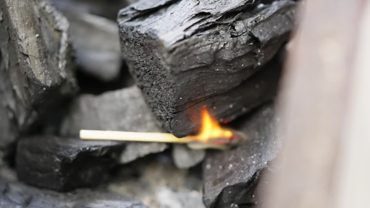 Close-up of charcoal being ignited with flames, symbol of cooking, warmth and preparation
