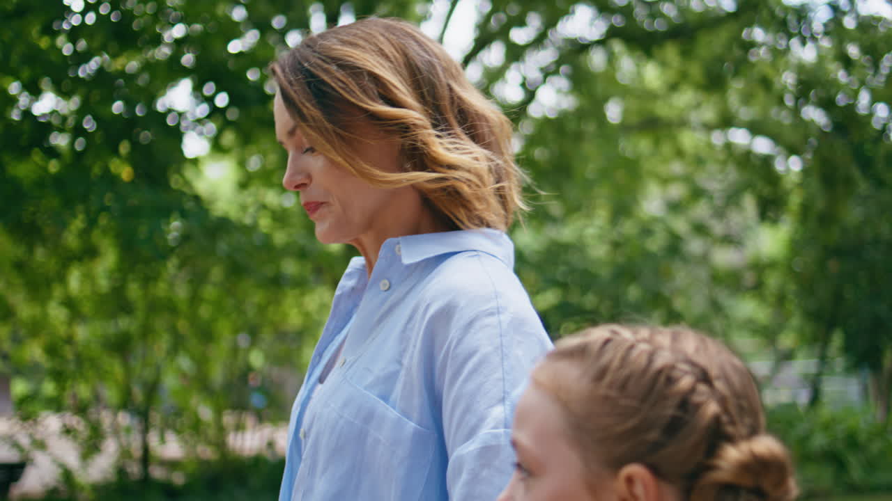 Mother walking greenery park with unknown child closeup. Family going garden