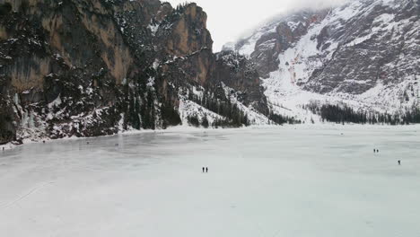 drone flying over frozen lake braies in trentino with people walking on cold winter day