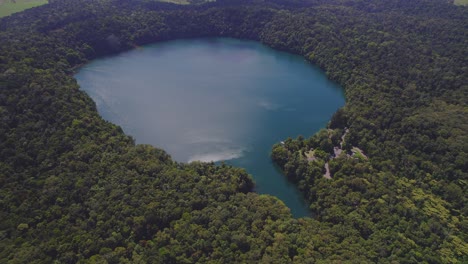 Vista-Aérea-Sobre-El-Lago-Eacham-Y-Su-Exuberante-Selva-Tropical-En-La-Meseta-De-Atherton,-Queensland,-Australia---Disparo-De-Drones