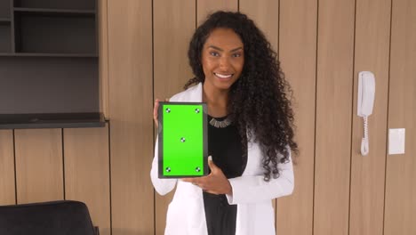 beautiful-black-woman-holding-tablet-green-background-vertical-smiling