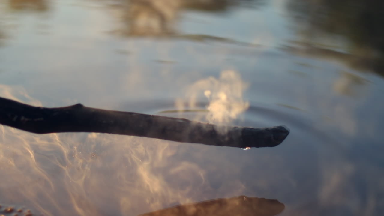 Smoke rising from stick as it goes underwater sizzling