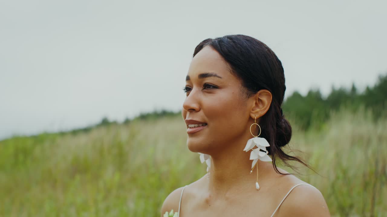 Woman with flower earrings in field