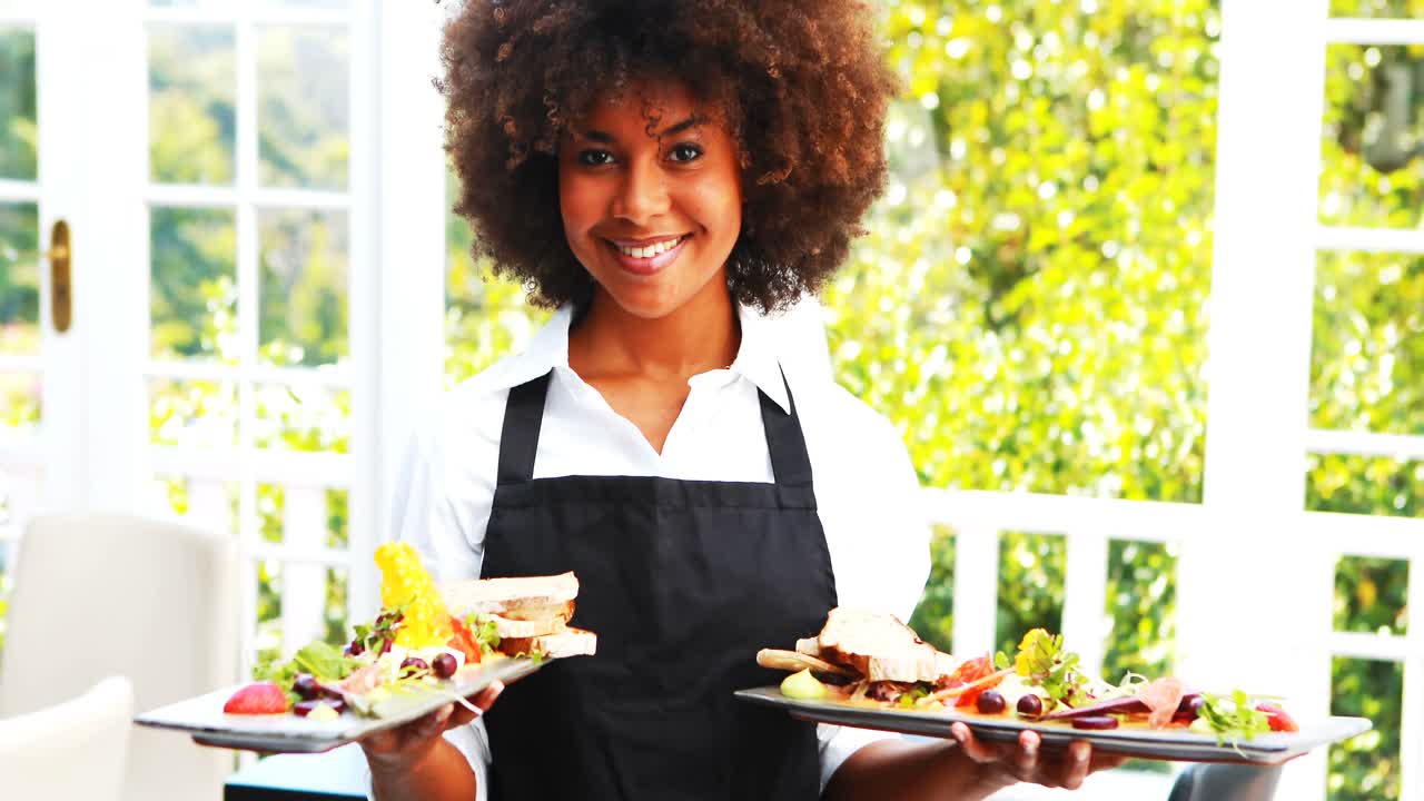 Portrait d'une serveuse souriante tenant un plateau repas