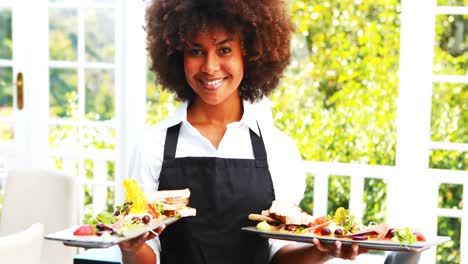 portrait of smiling waitress holding food tray