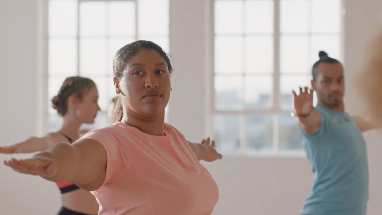 clase de yoga mujer joven con sobrepeso ejercitando un estilo de vida saludable practicando pose de guerrero disfrutando de entrenamiento físico para perder peso en el estudio al amanecer