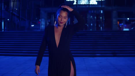 mujer joven disfrutando de la ciudad por la noche con un vestido negro con luces de la ciudad en el fondo