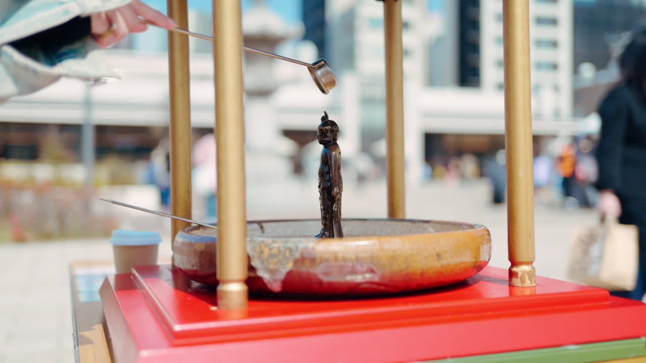 Close up of a purification water fountain at the Tsukiji Hongan-ji Temple with people walking on the blurred background