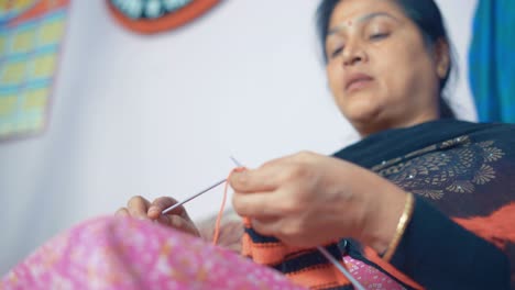 Imágenes-De-Abajo-De-Una-Mujer-India-Tejiendo-Una-Bufanda-Con-Lana-Roja-Y-Negra-Y-Dos-Agujas-Artesanales