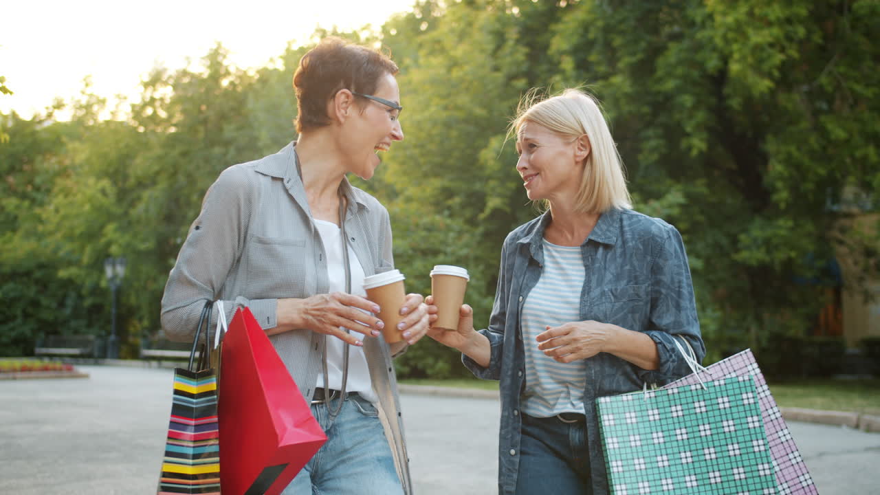 Two Women Enjoying a Coffee Break After Shopping in a Park