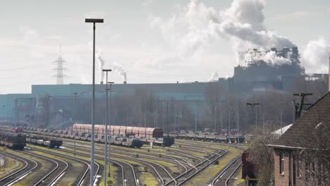 industrial railway yard with multiple tracks and freight cars, factory in the background