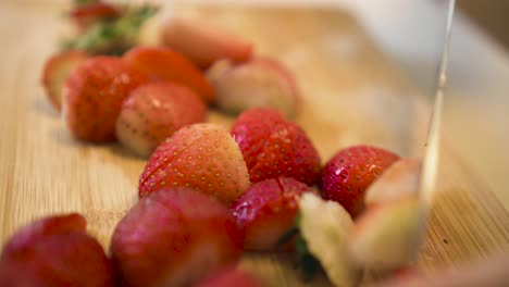 close up of feminine hands cutting delicious strawberry fruits at the kitchen