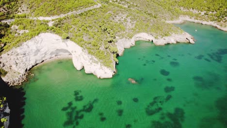 drone volando alto en movimiento circular con la cámara inclinándose lentamente sobre la escarpada costa del parque nacional de gargano, italia en 4k