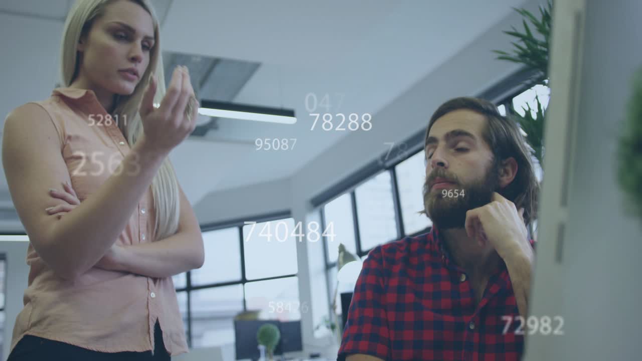 Seated man sketching woman walking pointing, data floating over screen, he pausing for design notes