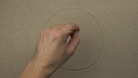 male hand draws a happy symbolic face on the sand of a person. top view