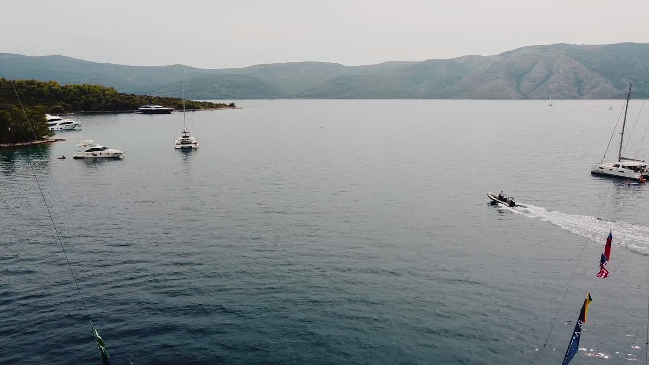 Drone shot of a yachts cruise, and a sailing speed boat in blue sea in the ocean, island background, green trees