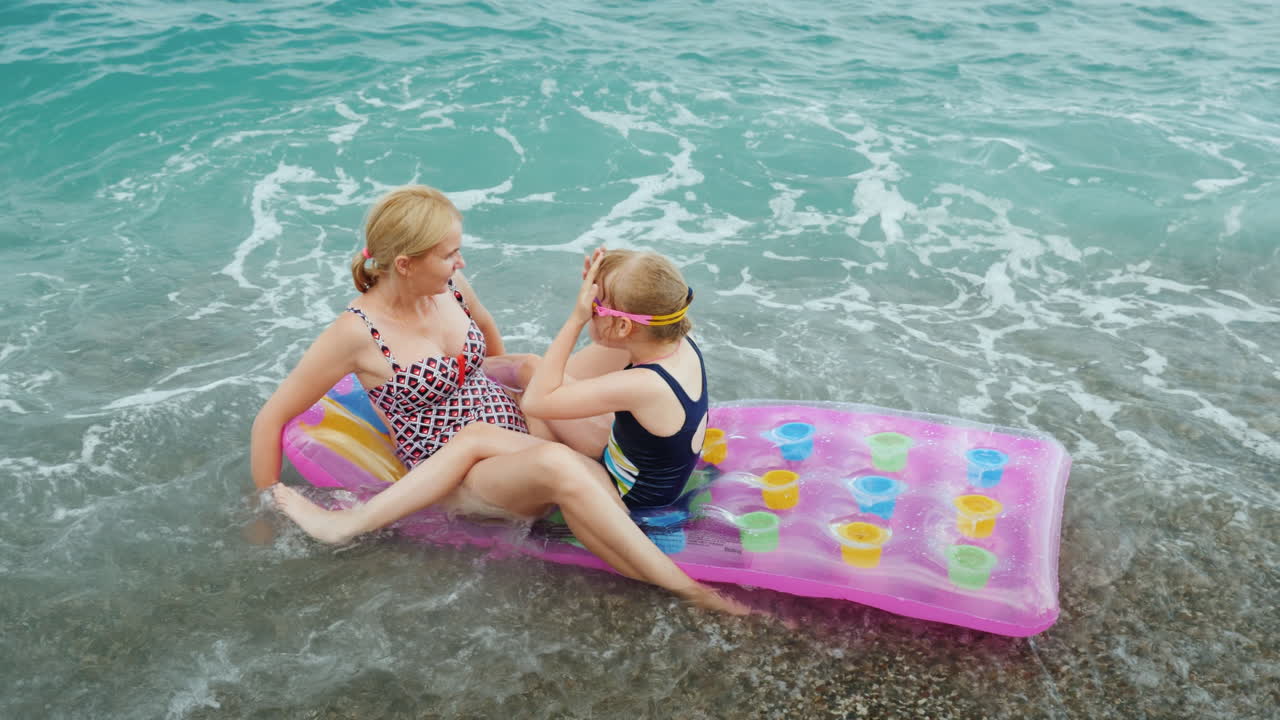 grandes olas del mar llevan un colchón inflable con una madre y un niño un paseo divertido en la ola