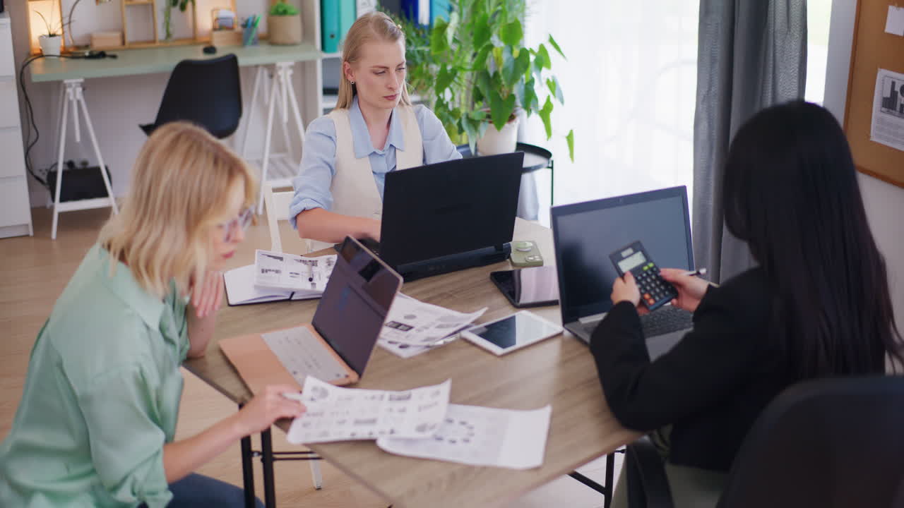 Three Female Colleagues Working on Laptops in Office