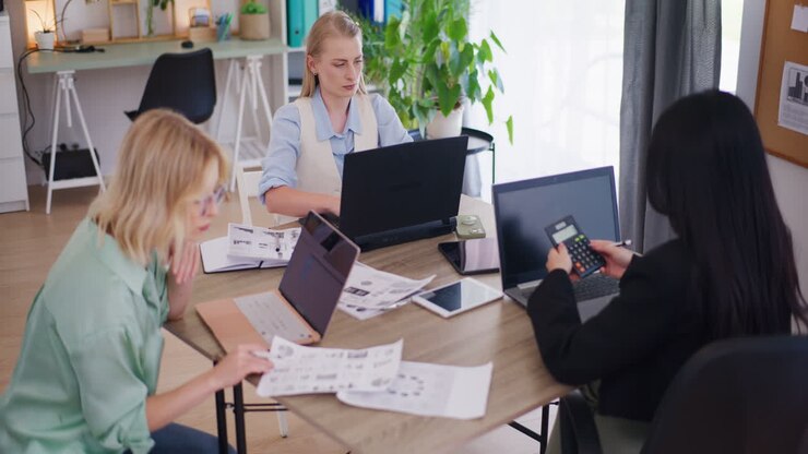 Three Female Colleagues Working on Laptops in Office