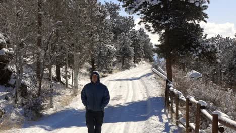 A-man-bundled-up-in-a-coat-walking-past-the-camera-on-a-snow-covered-road