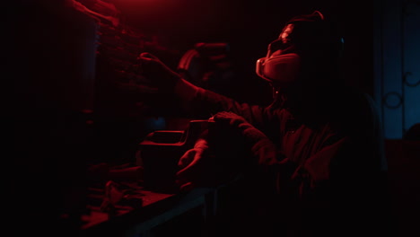 worker repairing machinery in a dark workshop with red light