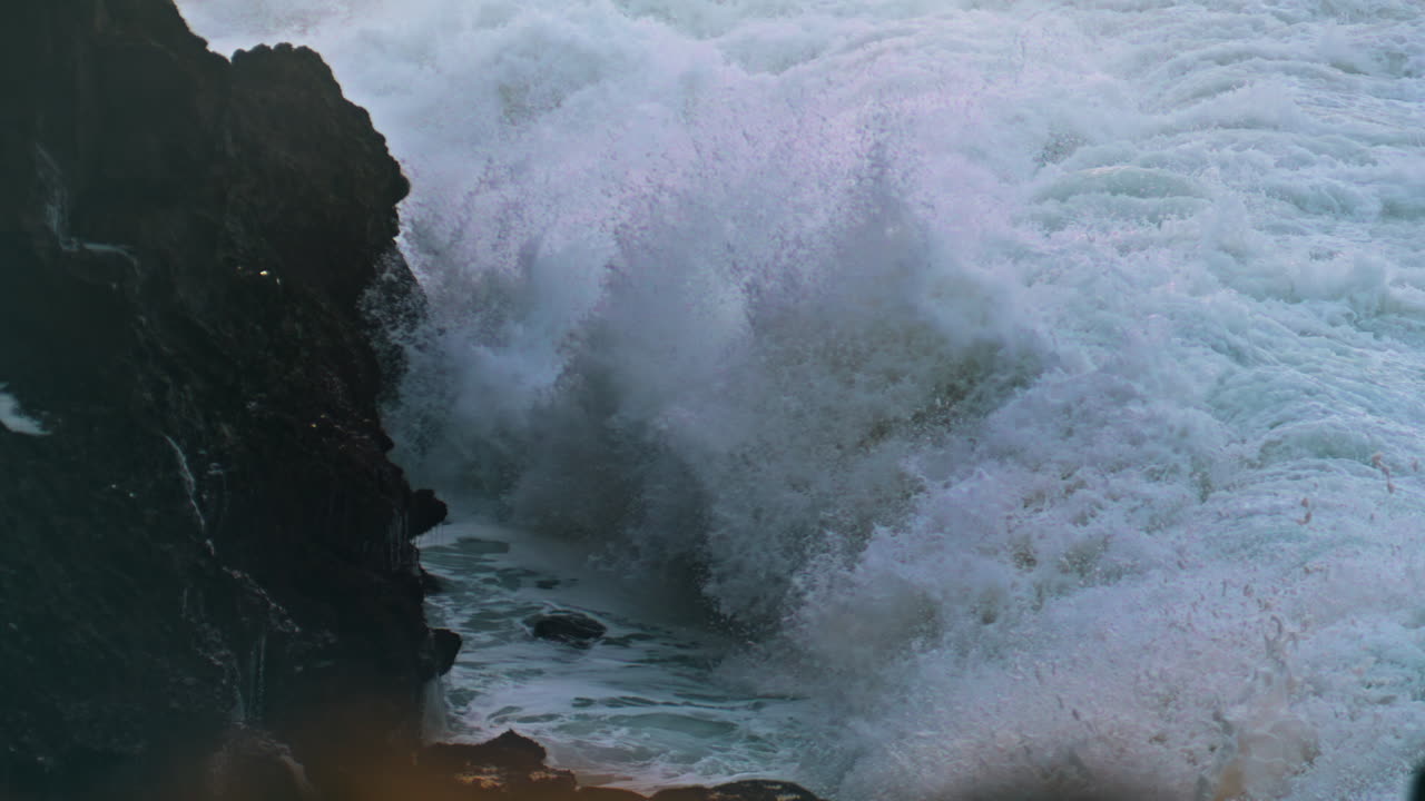 Splashing waves hitting cliff on stormy day. Powerful ocean breaking coastline
