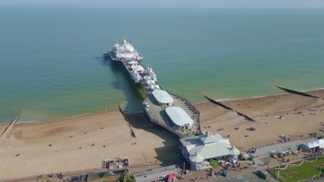 Flying-around-Eastbourne-Pier,-sea-front-and-beach